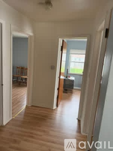 A hallway with a wooden floor and white walls.