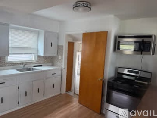 A kitchen with white cabinets and a wooden door.