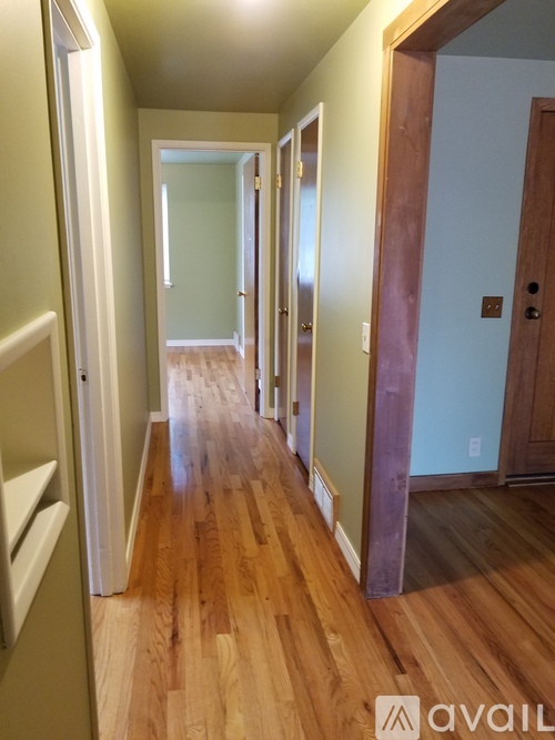 A hallway with wooden floors and white walls.