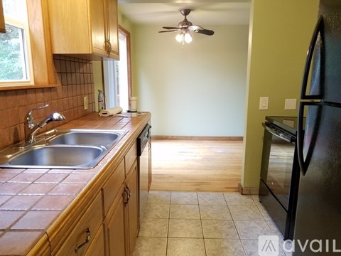 A kitchen with wooden cabinets and a black refrigerator.