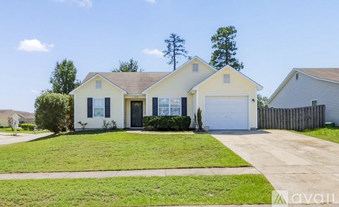A two-story house with a garage is surrounded by a wooden fence and has a well-maintained lawn.