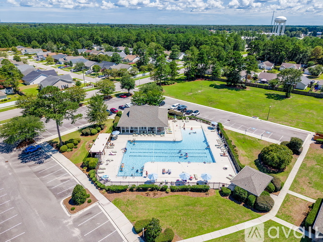 An aerial view of a swimming pool surrounded by a grassy area and residential houses.