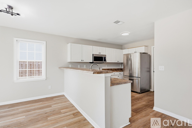 A kitchen with white cabinets and a wooden floor.