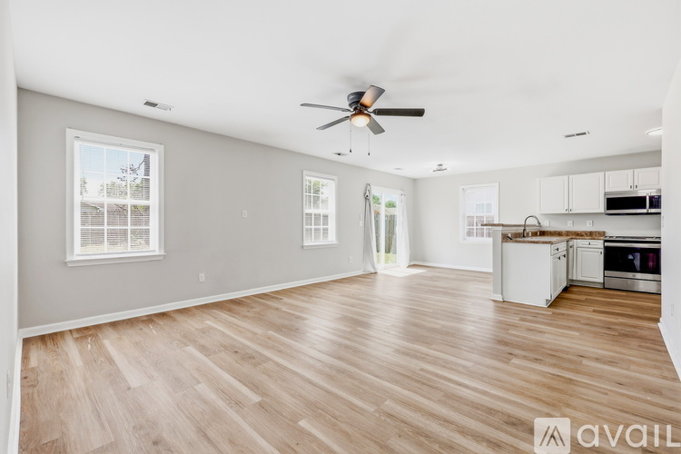 A spacious living room with a ceiling fan and hardwood flooring.