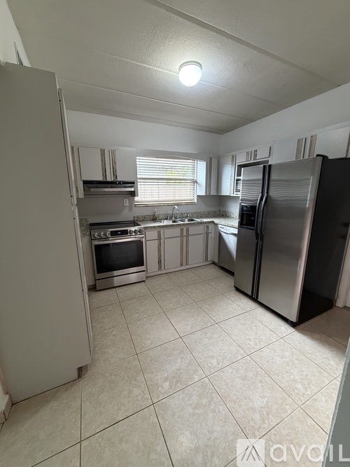 A kitchen with a refrigerator, oven, and microwave.