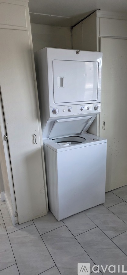 A white oven with a door open is in a room with white walls.