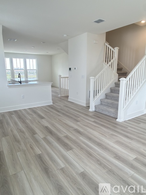 A spacious room with a staircase and a kitchen area.