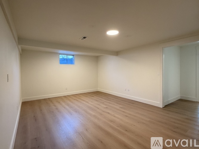 A spacious room with wooden flooring and a window.