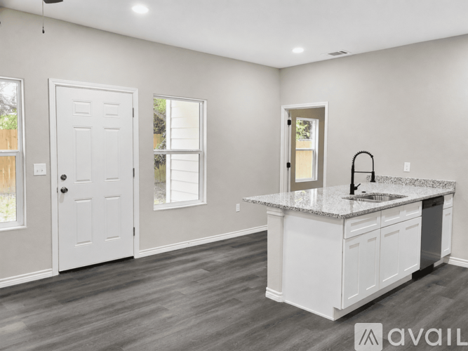 A kitchen with white cabinets and a granite countertop.