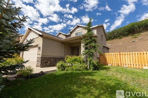 A house with a brown fence and green plants in front.
