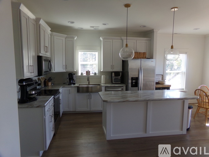 A kitchen with white cabinets and a marble island.
