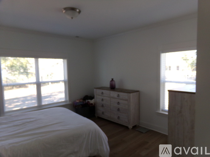 A bedroom with a bed, dresser, and window.