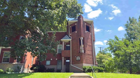A red brick building with a tower and a clock on the front.