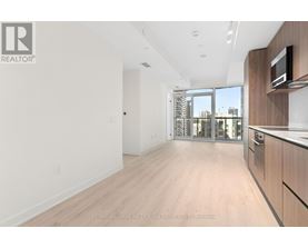 A spacious, empty room with wooden flooring and a large window.