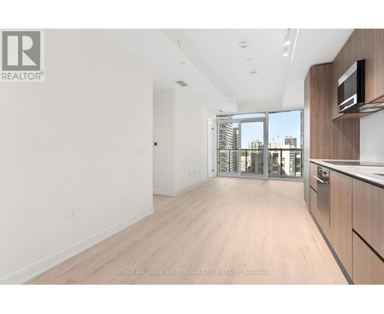 A spacious, empty room with wooden flooring and a large window.