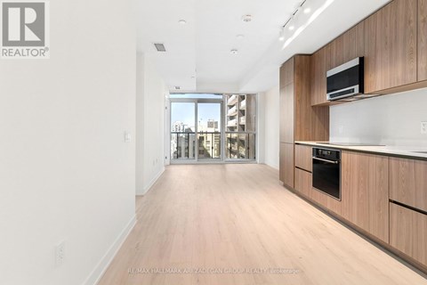 A spacious kitchen with wooden cabinets and a microwave on top.
