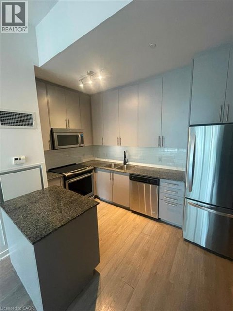 A modern kitchen with stainless steel appliances and wooden floors.