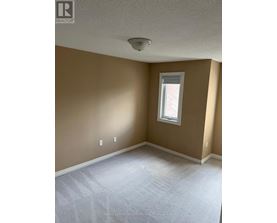 A room with a window and a carpeted floor.