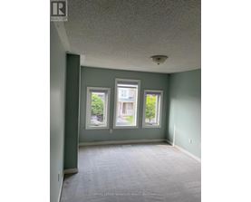 A room with a carpet floor and three windows.