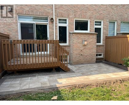 A small balcony with a wooden railing is in front of a brick building.