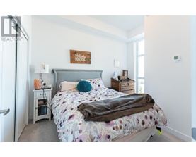 A bedroom with a bed, nightstand, and a sign on the wall.