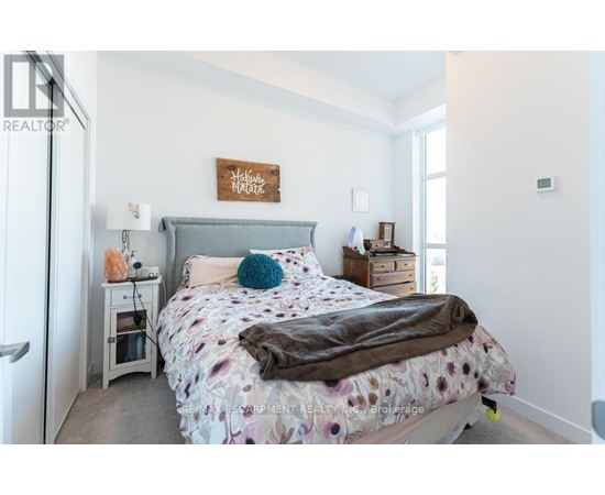 A bedroom with a bed, nightstand, and a sign on the wall.