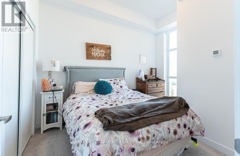 A bedroom with a bed, nightstand, and a sign on the wall.