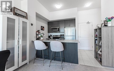 A modern kitchen with a bar area and two stools.
