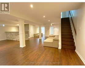 A spacious room with wooden floors and a staircase.