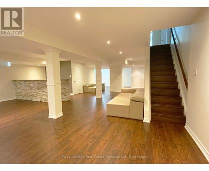 A spacious room with wooden floors and a staircase.