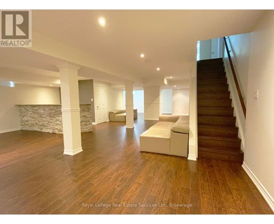 A spacious room with wooden floors and a staircase.