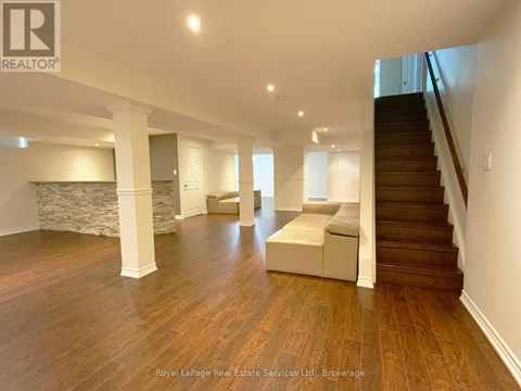 A spacious room with wooden floors and a staircase.