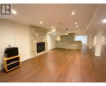 A spacious living room with wooden flooring and a stone fireplace.