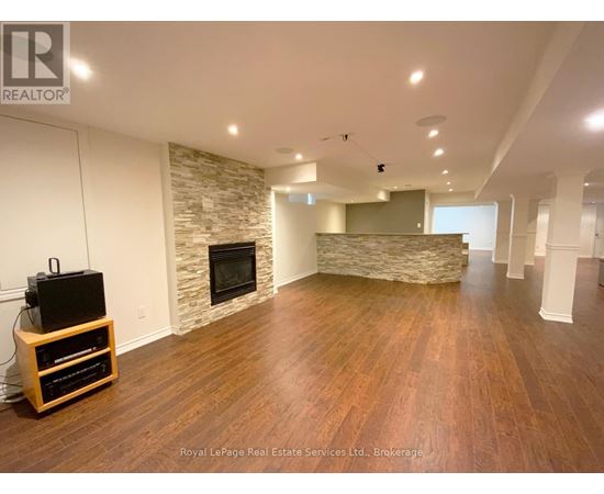 A spacious living room with wooden flooring and a stone fireplace.