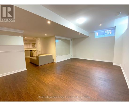 A spacious room with wooden flooring and white walls, featuring a built-in bench and a window.