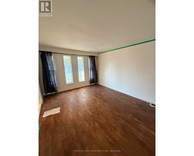 A room with wooden flooring and a window with curtains.