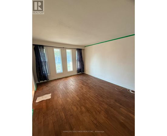 A room with wooden flooring and a window with curtains.