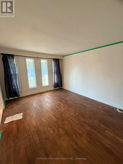 A room with wooden flooring and a window with curtains.