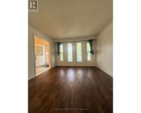 A room with wooden floors and a window with curtains.