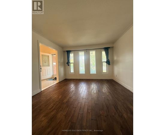 A room with wooden floors and a window with curtains.