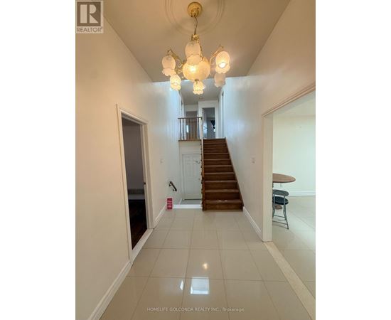 A hallway with a staircase and a chandelier.