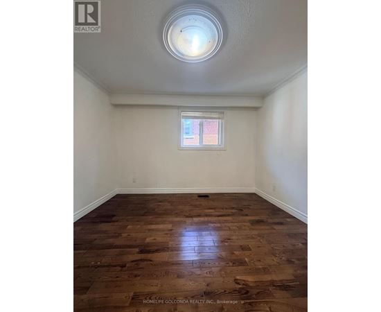 A room with wooden flooring and a window with blinds.