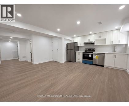 A spacious kitchen with white cabinets and a wooden floor.
