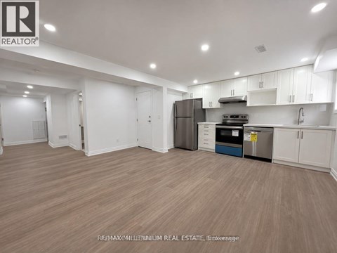 A spacious kitchen with white cabinets and a wooden floor.