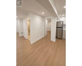 A spacious room with a refrigerator and wooden flooring.