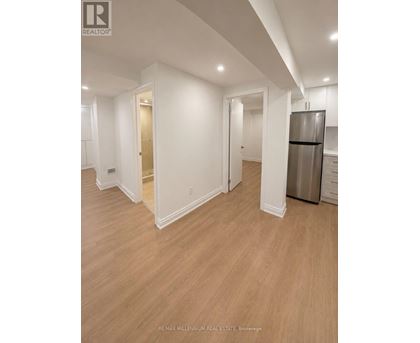 A spacious room with a refrigerator and wooden flooring.