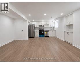 A spacious kitchen with white cabinets and a wooden floor.