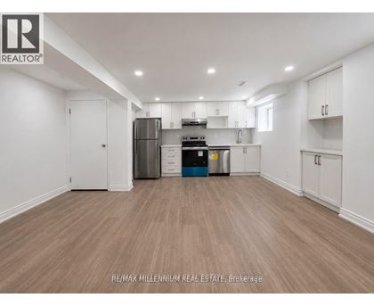 A spacious kitchen with white cabinets and a wooden floor.