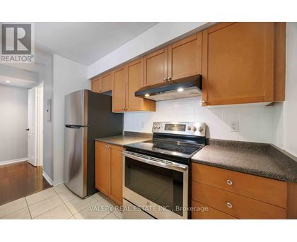 A kitchen with wooden cabinets and a stainless steel refrigerator.