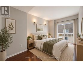 A bedroom with a bed, nightstand, and a plant.